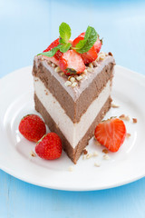 piece of chocolate cake of three layers with fresh strawberries