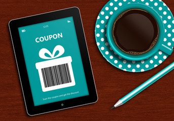 tablet with discount coupon and  cup of coffee lying on desk