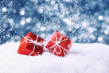 Two red gift boxes in snow on abstract background