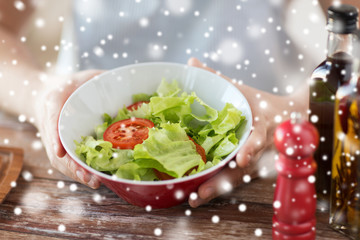 close of male hands holding bowl with salad