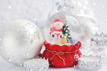 Fototapeta na wymiar A snow globe with snowman and Christmas decorations