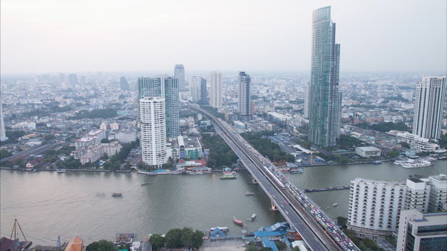 Timelapse day to night hight view of Bangkok city with modern building,that cover with mist, and traffic at evening until sunset along Chaopraya river