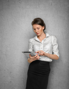 Pretty girl with tablet in their hands against the concrete