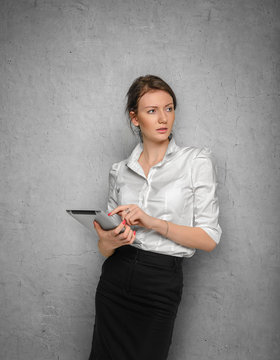 Pretty girl with tablet in their hands against the concrete