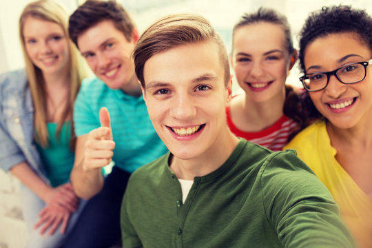 five smiling students taking selfie at school