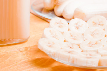peeled and sliced banana on a yellow table next banana juice