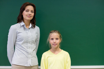 little school girl with teacher at blackboard