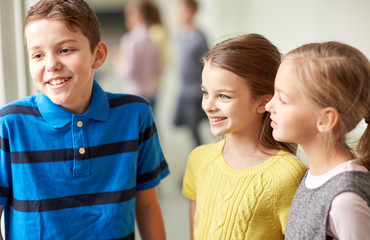 group of smiling school kids talking in corridor