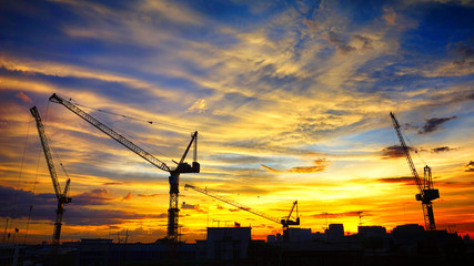 Industrial landscape with silhouettes of cranes on the sunset ba