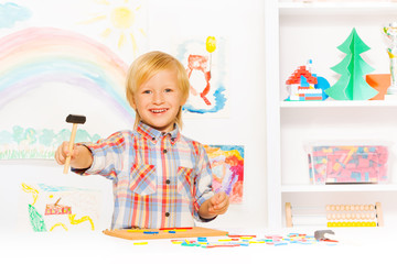 Fototapeta premium Happy blond boy with hammer and blocks in class
