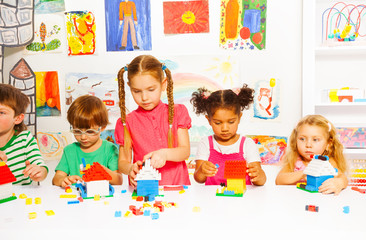 Naklejka premium Group of happy kids play with plastic blocks