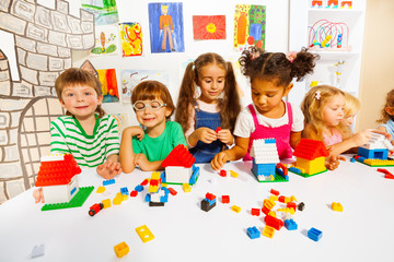 Many kids play with plastic blocks in classroom