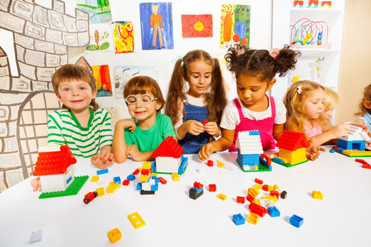 Many kids play with plastic blocks in classroom