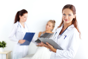 Fototapeta premium Smiling female doctor with a folder in uniform standing at