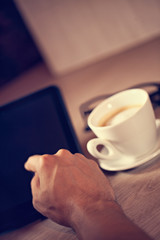 Human Hand Using Digital Tablet And Cup Of Coffee Behind