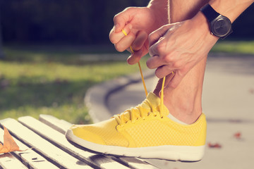 Tying running sneakers on a park bench.