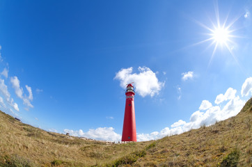 sun shining over red lighthouse