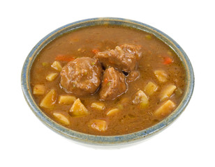 A large serving of meatball stew in an old bowl