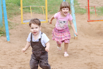 Little Boy in overalls runs away from girl