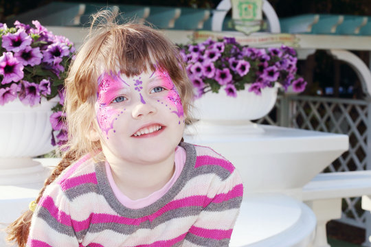 Happy little girl with pictured purple butterfly on face