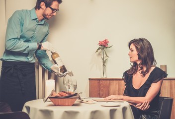 Waiter offering wine to lady in restaurant