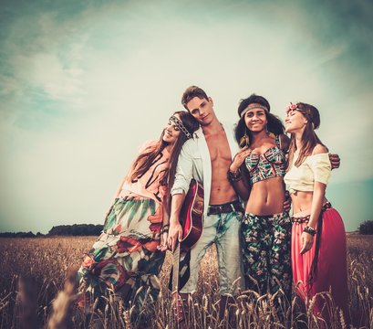 Multi-ethnic hippie friends with guitar in a wheat field