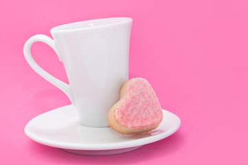 tasse de café avec petit-four en cœur  sur fond rose,