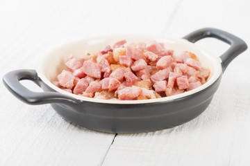 Lardons - Fried cubed pork belly on a white background.