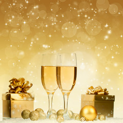 Glasses with champagne and gift box over sparkling holiday backg
