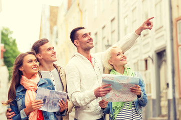 group of smiling friends with city guide and map