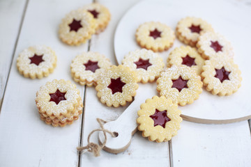 Weihnachtsplätzchen mit Himbeerkonfitüre auf einem Holzbrett