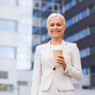 smiling businesswoman with paper cup outdoors