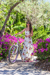 Young beautiful woman on vacation biking at lush garden