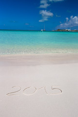 Fototapeta na wymiar 2015 written on tropical beach white sand with xmas hat