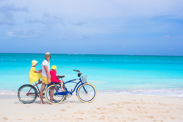 Fototapeta premium Happy dad and cute girls riding bicycles on tropical beach