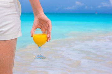 Orange juice in female hand on background of the sea