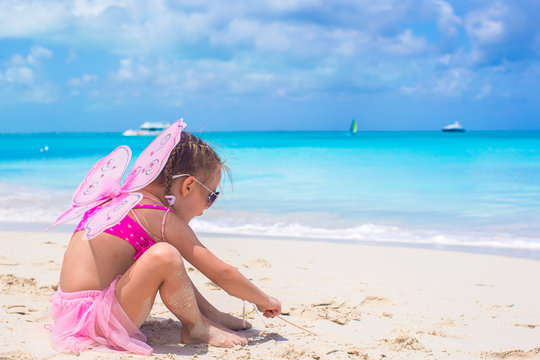 Adorable little girl with wings like butterfly on beach vacation