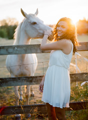 Smiling Young Woman Petting a Horse at Sunset