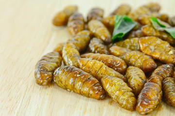 fried silk worms on cutting board for food concept