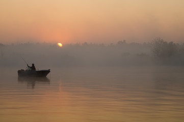 wędkarz na łodzi łowiący w mglisty poranek