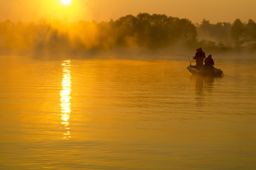 wędkarze na łodzi łowiący w mglisty poranek