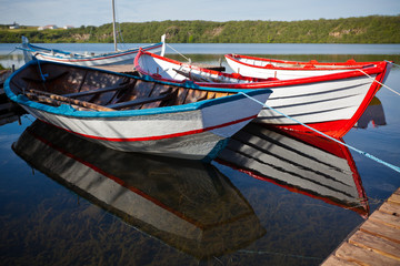 Fototapeta na wymiar Floating Color Wooden Boats with Paddles in a Lake