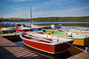 Obraz premium Floating Color Wooden Boats with Paddles in a Lake