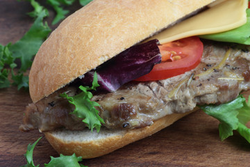 Sandwich with pork steak, tomato, cheese and lettuce.