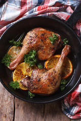 Roast duck leg with oranges and parsley vertical top view