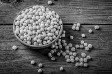 dry peas in a bowl on old wooden table. black and white