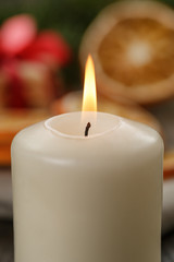 burning candle in front of christmas table