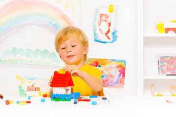Fototapeta premium Handsome blond boy playing with plastic blocks