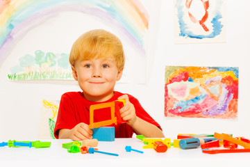 Little blond boy with hacksaw in classroom