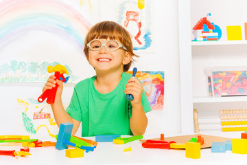 Smart boy in glasses with toy work tools
